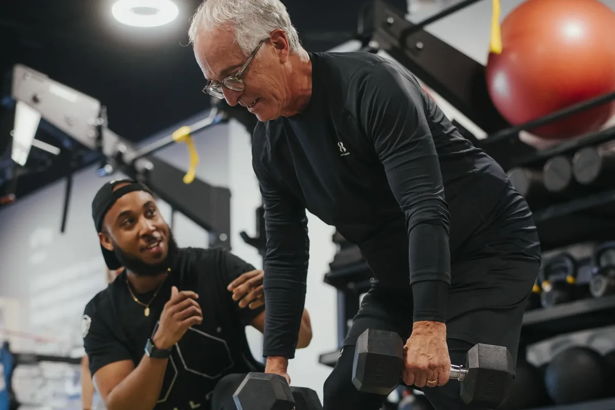 Alloy coach guiding a member through a dumbbell exercise during an introductory session